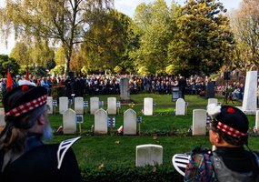 Bezoekers luisteren naar een toespraak bij de oorlogsgraven
