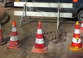 het gat in de weg is afgezet met een hek en pionnen