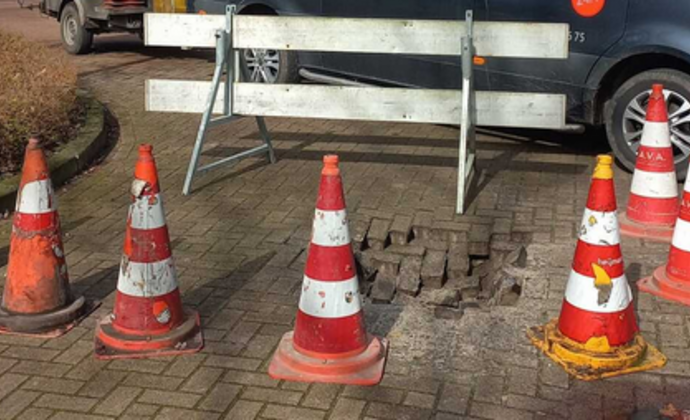 het gat in de weg is afgezet met een hek en pionnen