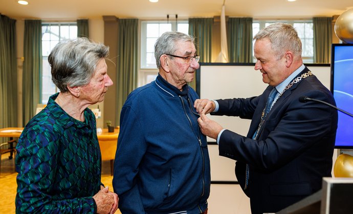 De burgemeester spelt Nico van Sabben een lintje op